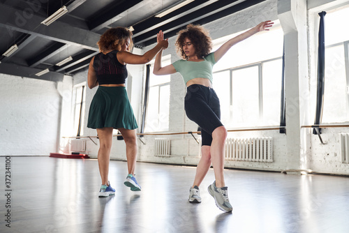Women holding hands and repeating movements in dance studio