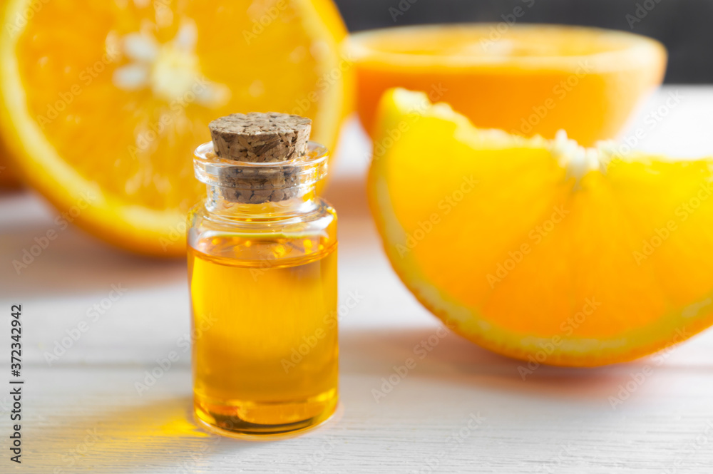 Natural orange essential oil in bottle and cut orange fruit on white wooden table. Natural orange essential oil in bottle and cut orange fruit on white wooden table.
