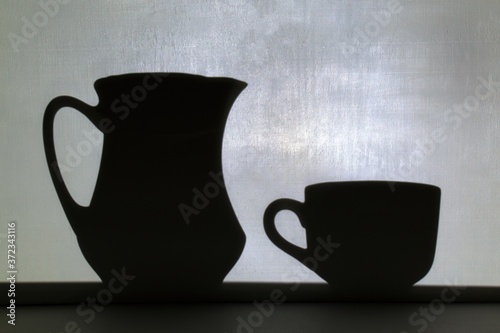 shadow from jug and mug on blurred white wall background