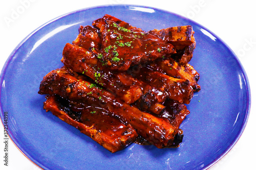smokey barbeque sauce glazed baby pork ribs in a plate with white background