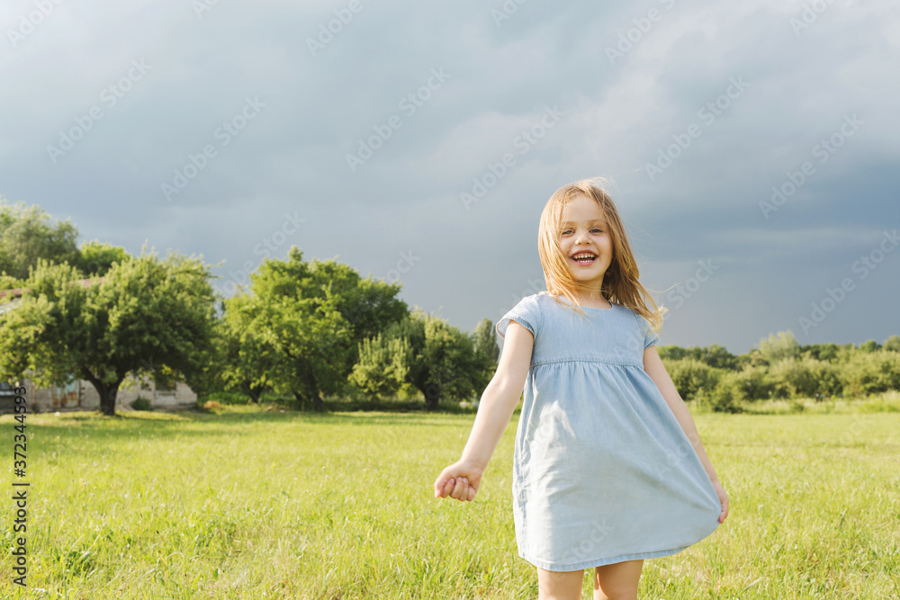 Little blond girl in a blue dress in the garden. Little blond girl in a blue dress in the garden.