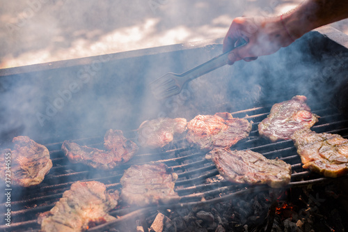 Young adult cooking steaks on barbecue photo