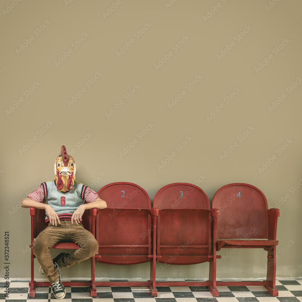 rooster masked boy on red retro cinema chairs