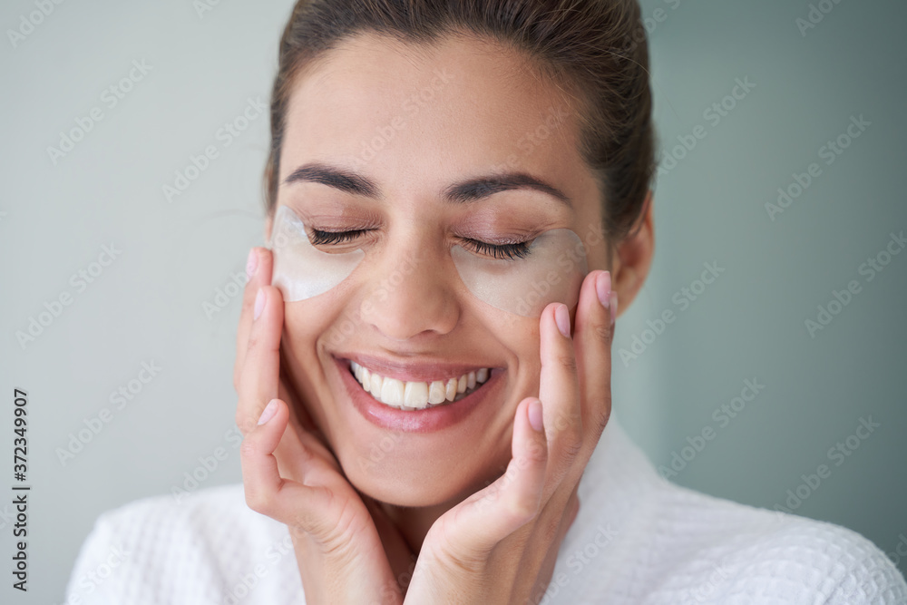 Delighted woman with under eye patches smiling Delighted woman with under eye patches smiling