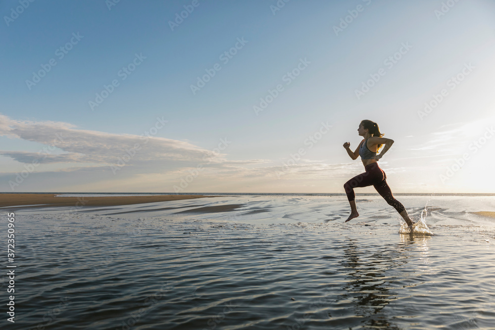 Beautiful Fit Female Athlete Running on Beach Beautiful Fit Female Athlete Running on Beach