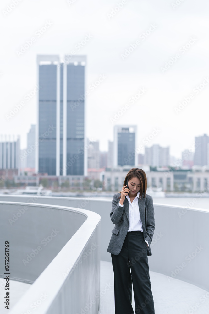 Business woman using cellphone on top of buildings Business woman using cellphone on top of buildings