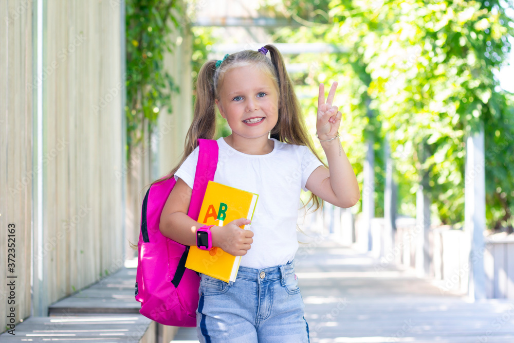 schoolgirl stands with a backpack and a textbook. copy space
