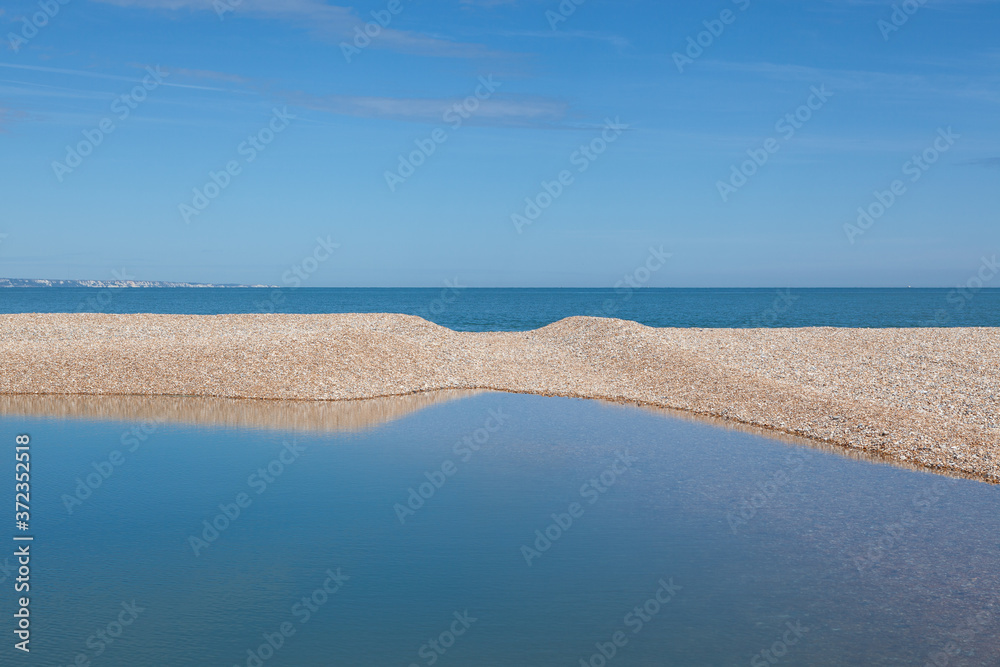 Pool of water on Dungeness beach; one of the largest shingle beaches in Europe. Stock Photo