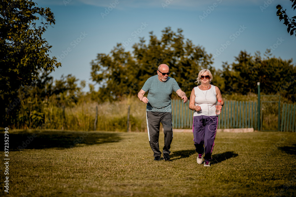 Fototapeta premium Senior couple running outside . Elderly man and woman jogging together.