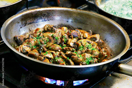 saute mushrooms in a cooking pan on fire
