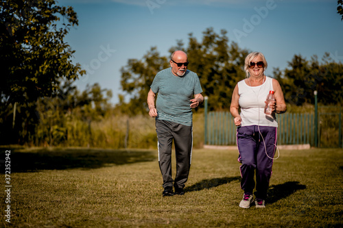 Senior couple running outside . Elderly man and woman jogging together.