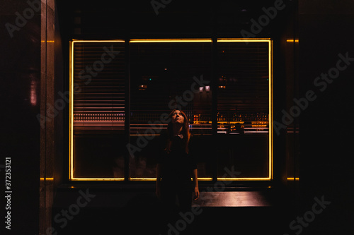Woman looking up with a square of lights behind