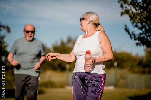 Fototapeta Naklejka Na Ścianę i Meble -  Senior couple running outside . Elderly man and  woman jogging together