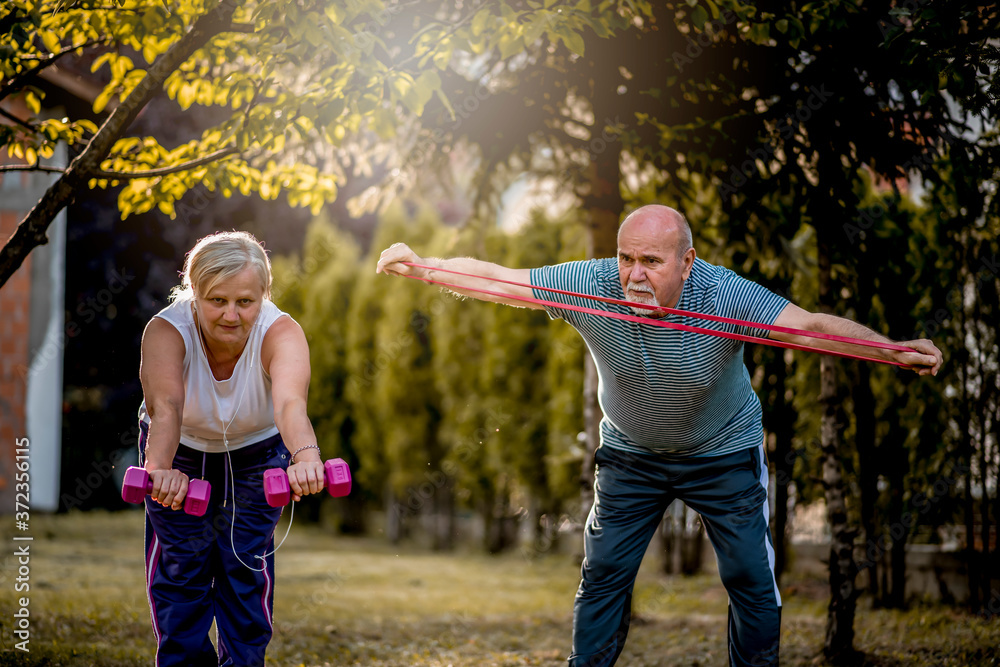 Healthy senior couple exercising with dumbbells and elastic band Healthy senior couple exercising with dumbbells and elastic band