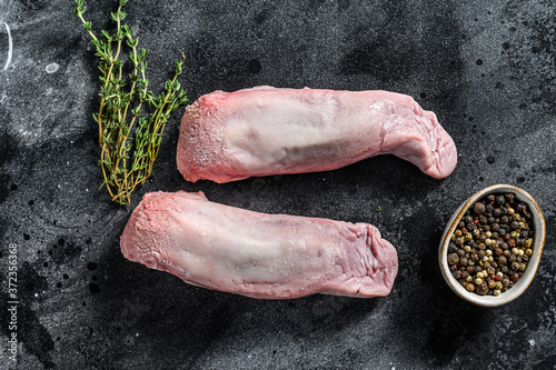 Raw pork tongue with spices and herbs. Black background. Top view