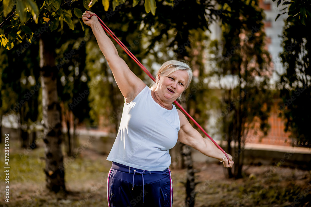 Senior woman exercising with elastic band outdoors 
