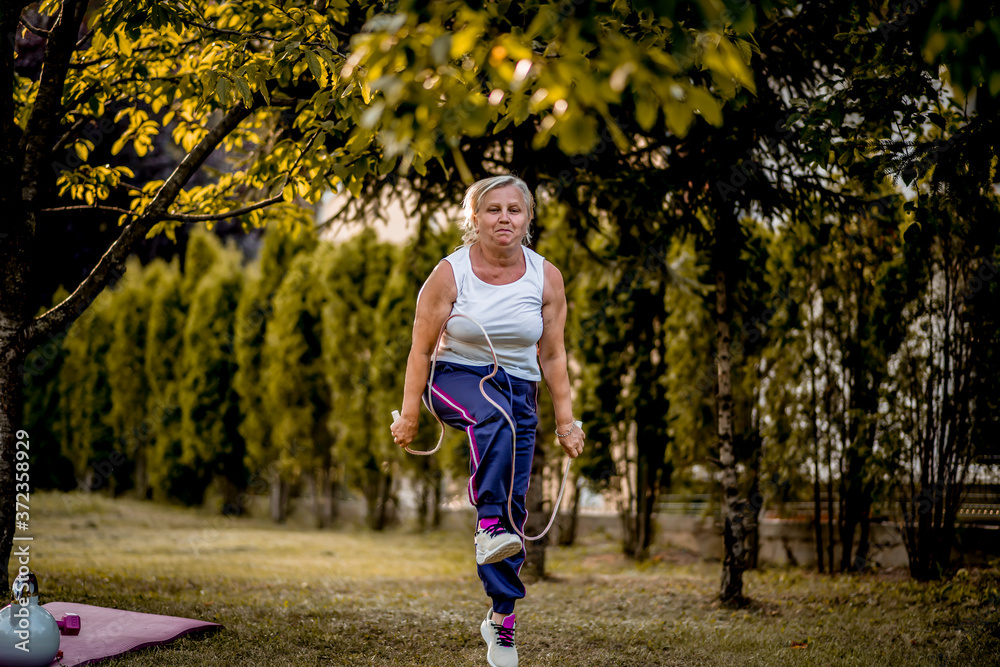 Senior woman exercising with jumping rope outdoors 