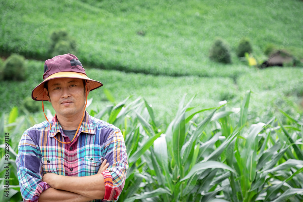Asian Farmer smile with hat stand in the corn plantation field on hill