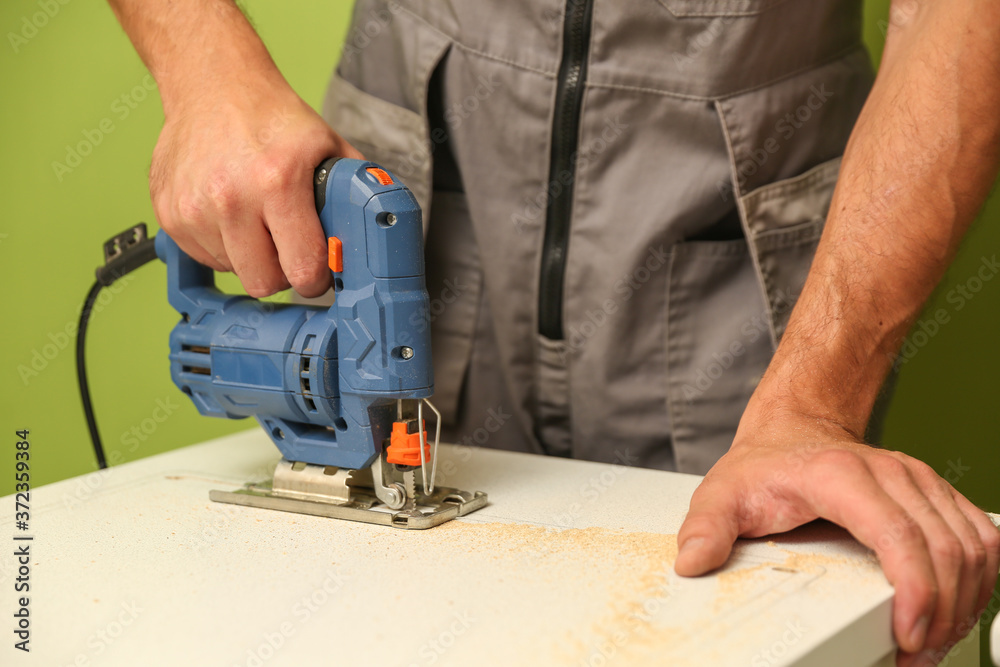 refurbishment in the apartment. carpenter's hands are sawing with electric jigsaw