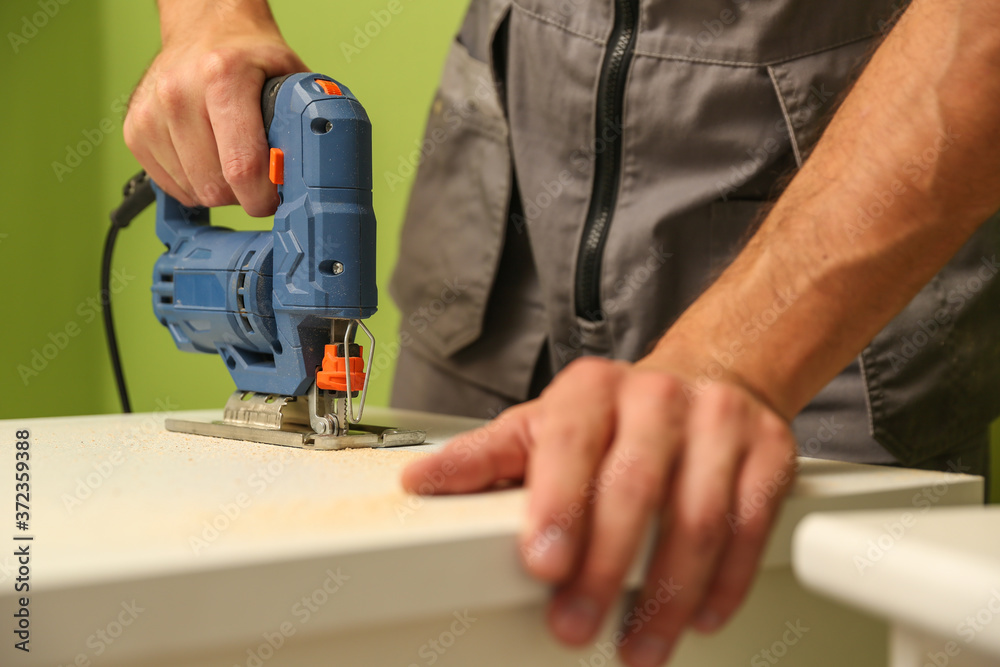 refurbishment in the apartment. carpenter's hands are sawing with electric jigsaw