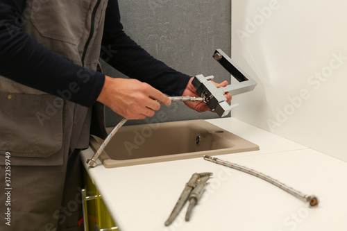 plumber installs kitchen faucet. refurbishment in the apartment. 
