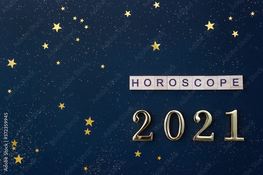 Word Horoscope and 2021 numbers. Wooden blocks with letters on blue background decorated with starry confetti. Copy space