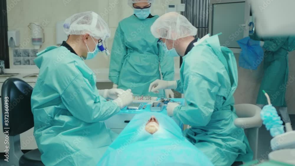 Dentist wear protective suit and gloves working on patient dental surgical operation with assistance specialist teamwork medical infectious disease hygiene slow motion Dentist wear protective suit and gloves working on patient dental surgical operation with assistance specialist teamwork medical infectious disease hygiene slow motion