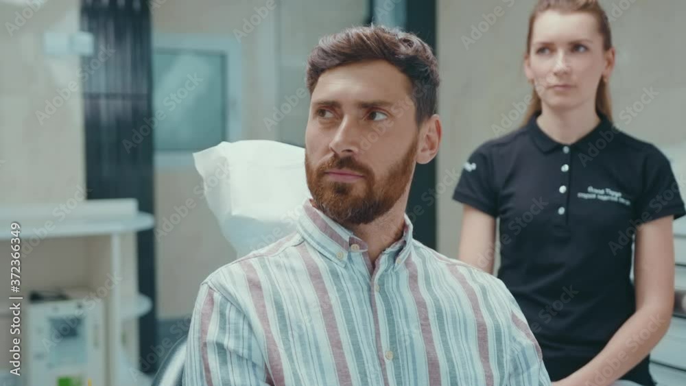 Happy portrait of handsome young male patient in dental chair talking looking smiling medical hygiene healthcare teeth patient equipment slow motion Happy portrait of handsome young male patient in dental chair talking looking smiling medical hygiene healthcare teeth patient equipment slow motion