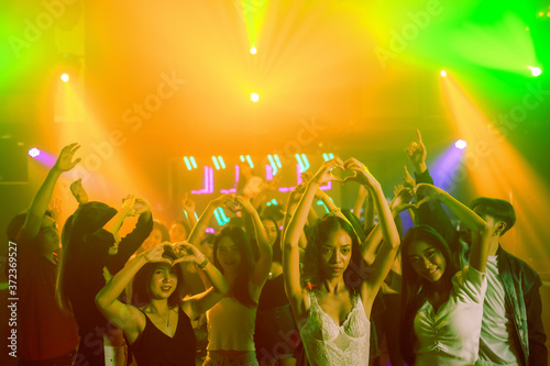 crowd of people raise hands and dancing in night club