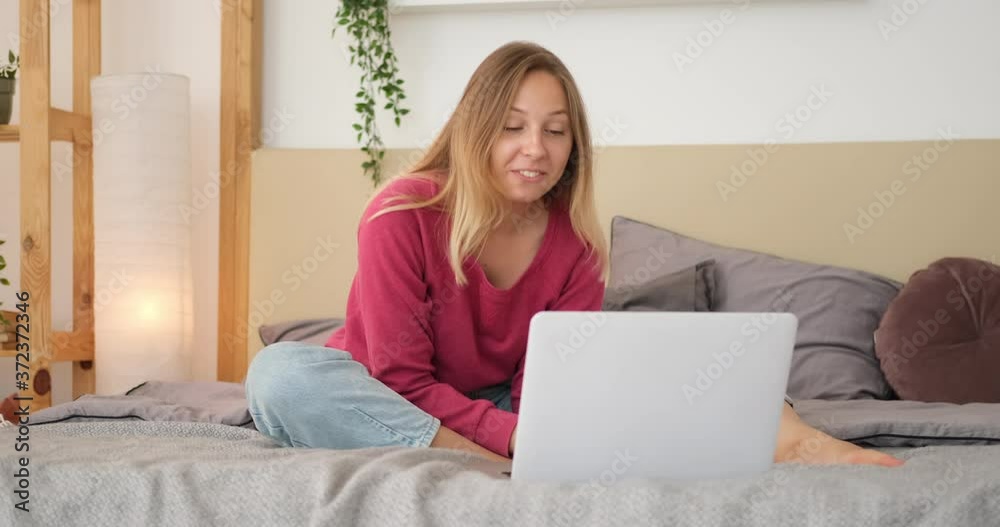 Woman doing video call using laptop sitting on bed at home Woman doing video call using laptop sitting on bed at home