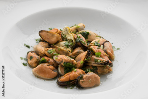 Mediterranean cuisine. Seafood. Closeup view of mussels with a traditional Provencal condiment, made with garlic and parsley, in a white dish.  photo