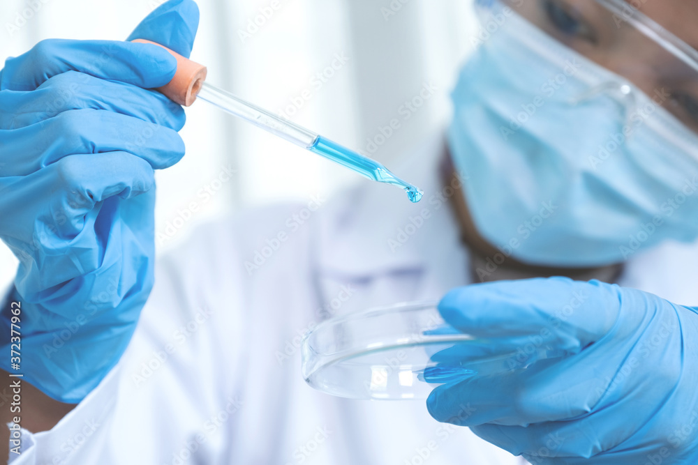 Scientists hand hold the pipette and drop the blue chemical liquid for research and analysis in a laboratory Scientists hand hold the pipette and drop the blue chemical liquid for research and analysis in a laboratory