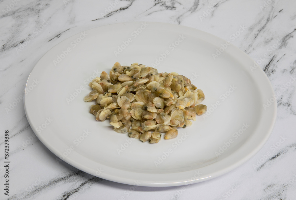 Gastronomy. Seafood ingredient. View of cockles on a white dish on the table. Gastronomy. Seafood ingredient. View of cockles on a white dish on the table.
