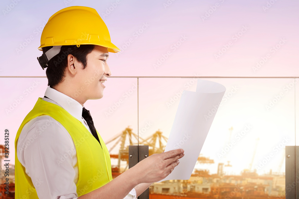 Asian construction worker with hardhat holding planning paper Asian construction worker with hardhat holding planning paper