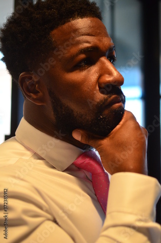 Portrait of Young African American man stares in the mirror while holding his beard