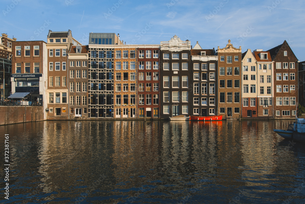 Canal houses in Amsterdam during sunset with calm reflection in the water