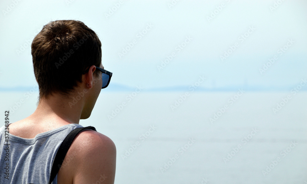 Young man in singlet and sunglasses looking at the Japanese sea. Much copy space Young man in singlet and sunglasses looking at the Japanese sea. Much copy space