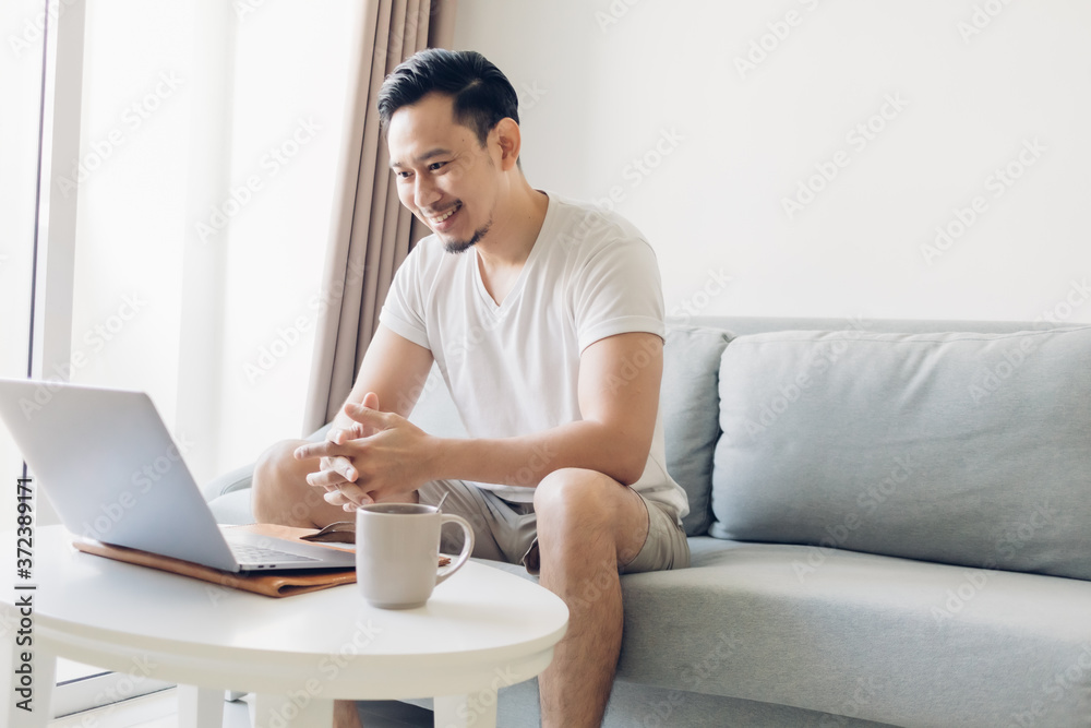 Happy Asian man is working on his laptop in the living room. Happy Asian man is working on his laptop in the living room.