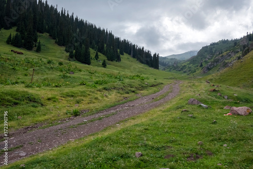 Beautifu lview of green mountains with dangerous gravel road. Ketmen or Ketpen mountains gorge and mountain pass. Tourism in Kazakhstan.