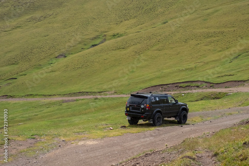 4x4 off-road SUV on gravel road in green mountains. Mountain trail landscape. Adventure travel. Ketmen mountain gorge and mountain pass in Kazakhstan. 25.07.2020 Almaty, Kazakhstan.
