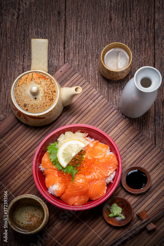 Delicious Donburi or Japanese rice bowl topped Sashimi Salmon Roe and Fish eggs on Bamboo table.