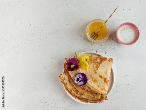 French crepes, pancakes decorated with flowers, a mug of cappuccino and honey. Concept of Breakfast, dessert. Copy space photo