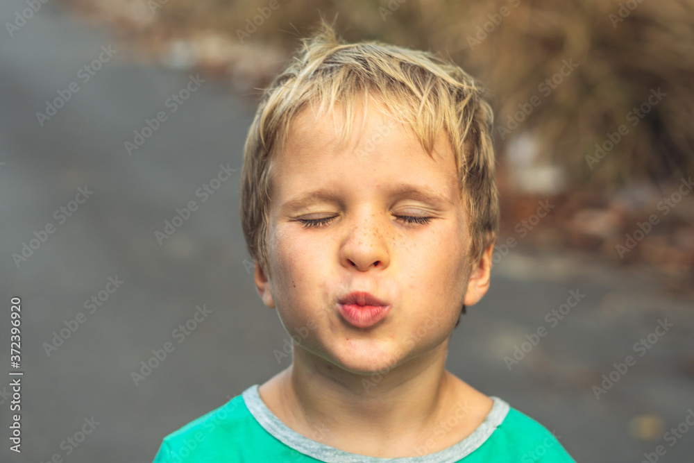Funny mischievous cute blond boy making freckles face showing love kiss, artistic emotions gesturing. Family relationship, micro moments joys of happy childhood, compassion toward humanity and society Funny mischievous cute blond boy making freckles face showing love kiss, artistic emotions gesturing. Family relationship, micro moments joys of happy childhood, compassion toward humanity and society