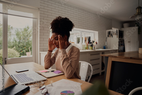 Young stressed woman holding hands on head while sitting in front computer laptop