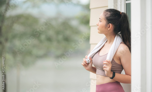 Young sportswoman with towel relaxing by standing outside at home after exercise, copy space. Free Download Young sportswoman with towel relaxing by standing outside at home after exercise, copy space. - GFXLoad