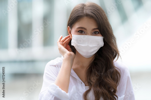 Portrait of young woman with smiley face wearing face mask protective walks in a city