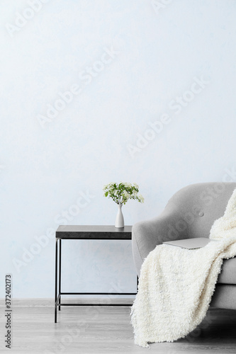 Soft armchair and table near light wall in room