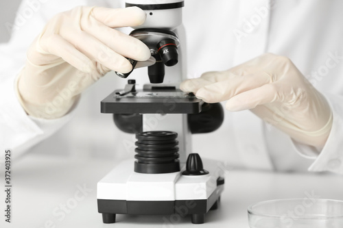 Scientist using microscope in laboratory, closeup