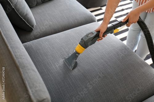 Woman removing dirt from sofa at home