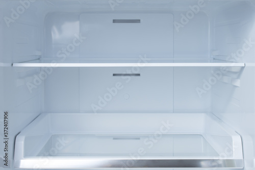 Shelves in empty open white fridge. Background empty shelves in the refrigerator.